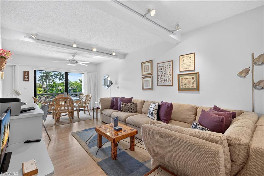 Spacious living area featuring light wood-finish flooring and track lighting