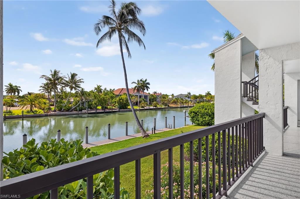 Waterfront balcony with a metal railing, overlooking a canal with boat docks