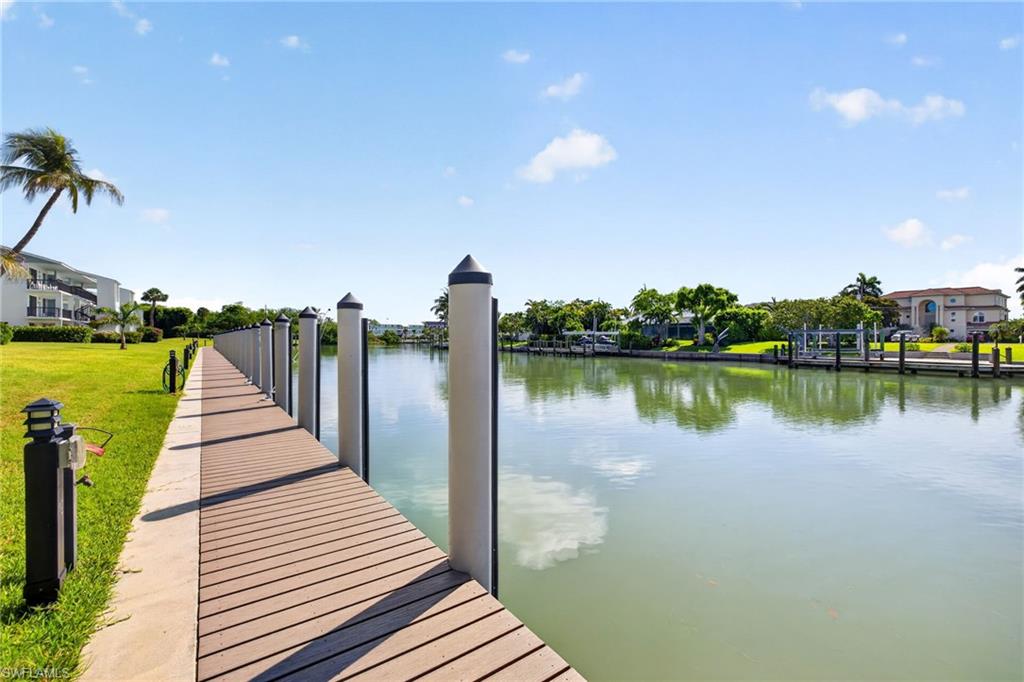 Extensive waterfront dock with wood-finish decking and multiple pilings, paralleling a tranquil canal