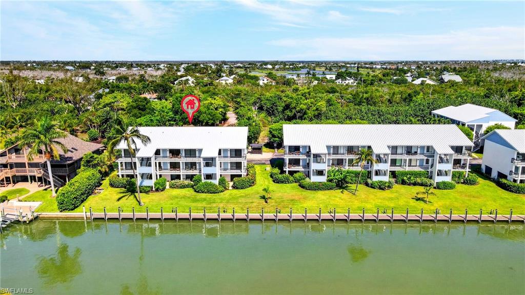 Waterfront condominium complex featuring multiple units with private balconies, manicured landscaping, and direct water access
