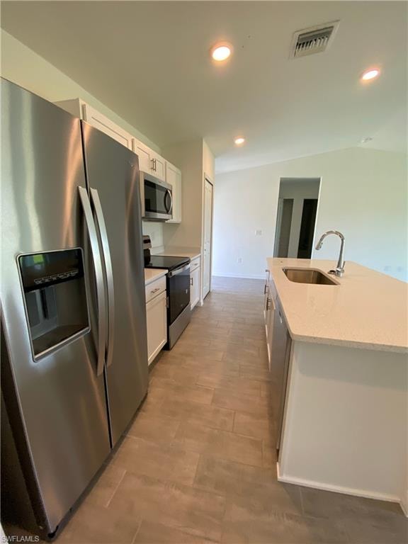 Kitchen with white cabinetry, light stone countertops, light wood-type flooring, appliances with stainless steel finishes, and sink