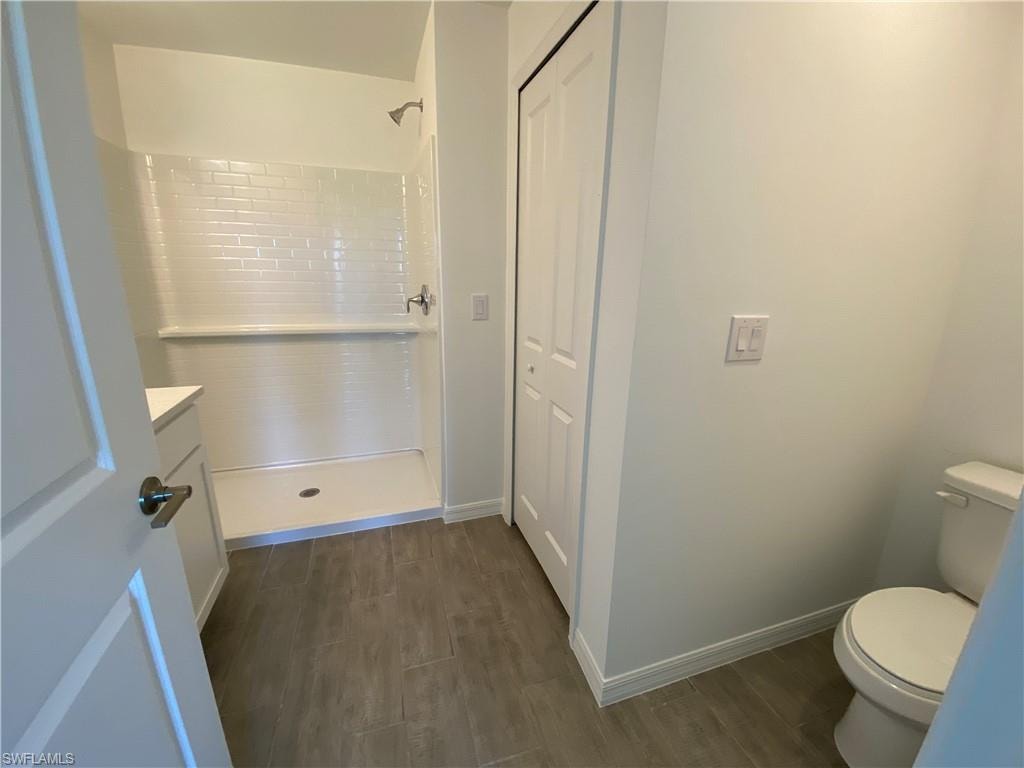 Bathroom with walk in shower, hardwood / wood-style floors, toilet, and vanity