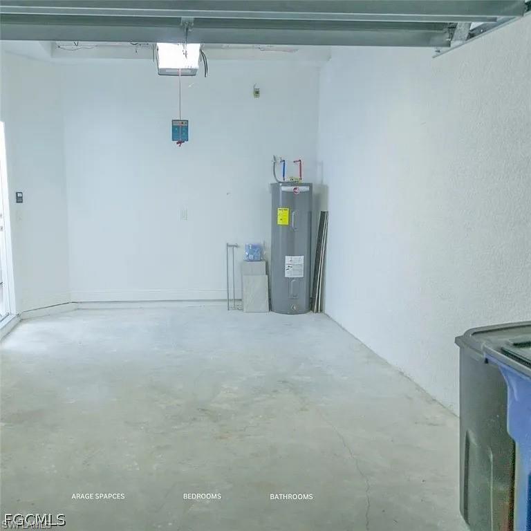 Garage interior featuring a concrete floor, painted walls, an overhead garage door mechanism, and a water heater