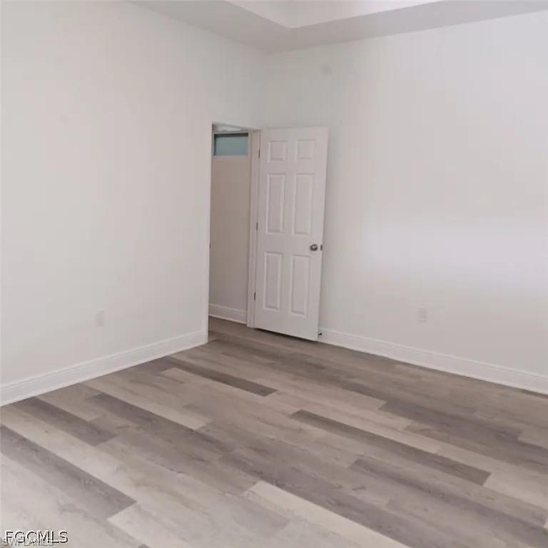 Room featuring light wood-finish flooring, white baseboards, and bright white walls
