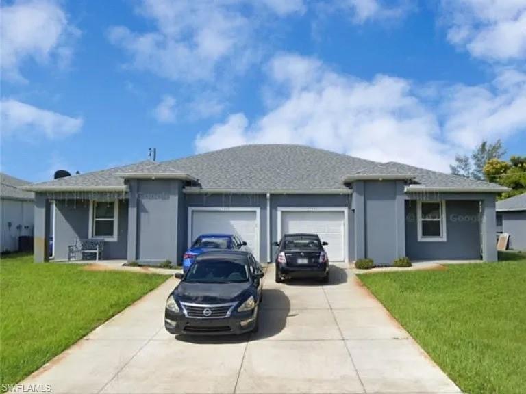 Duplex property featuring a grey exterior with white trim, two single-car garages, and separate concrete driveways