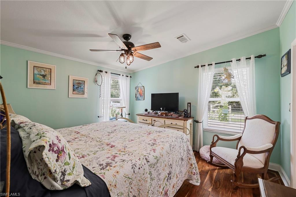 Interior room featuring wood-finish flooring, light green walls, and white crown molding