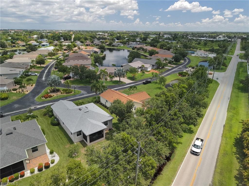 Residential neighborhood featuring a lake, mature trees, and paved roads