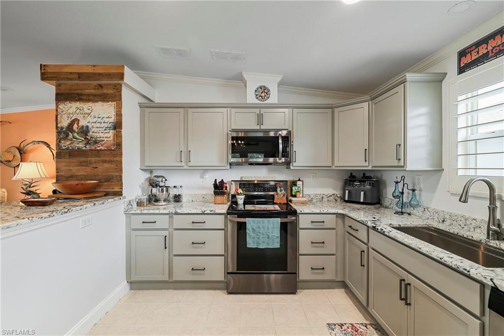 Modern kitchen featuring light gray cabinetry, stainless steel appliances, speckled countertops, and a stainless steel sink with a gooseneck faucet