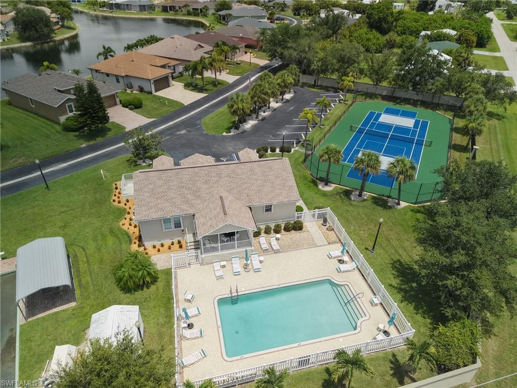 Community amenities featuring a fenced swimming pool, sun deck with lounge chairs, and a tennis court