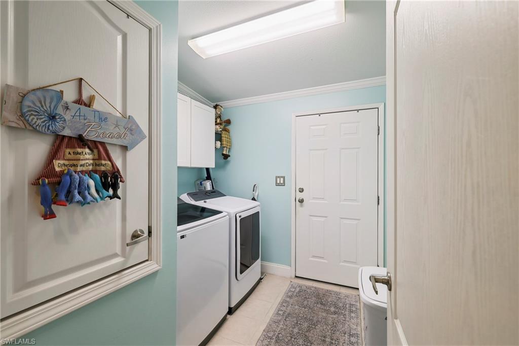 Dedicated laundry space featuring a white washer and dryer pair, upper cabinetry, and a full-light flush fluorescent ceiling fixture