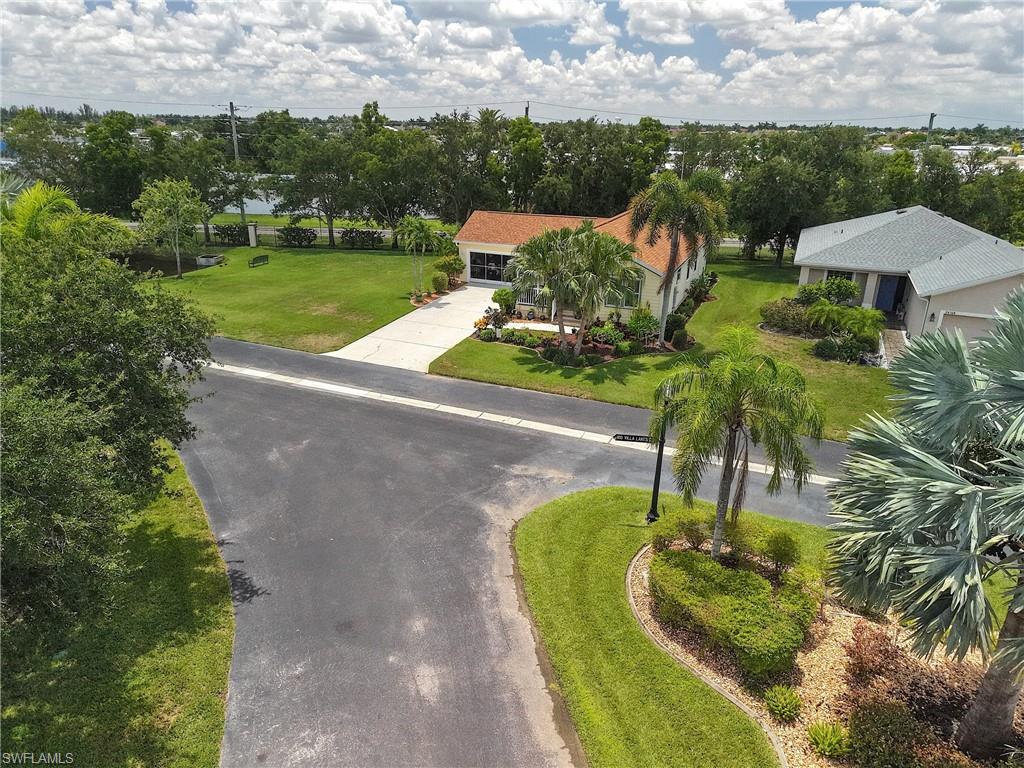 Paved driveway leading to a residence with a terracotta-style roof, surrounded by mature palm trees and established landscaping