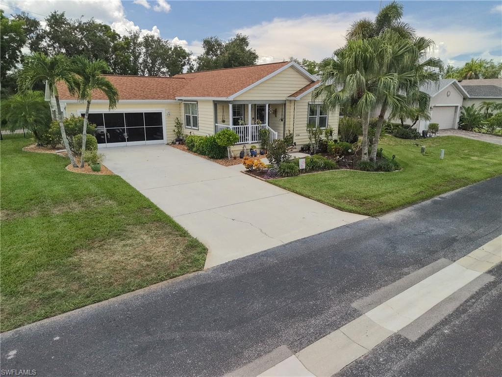 Single-story residence featuring a screened garage, concrete driveway, and front porch with white railing