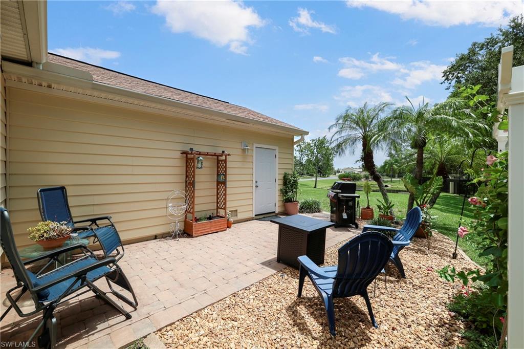 Paved patio with gravel landscaping, featuring mature palm trees, a vibrant green lawn, and exterior siding