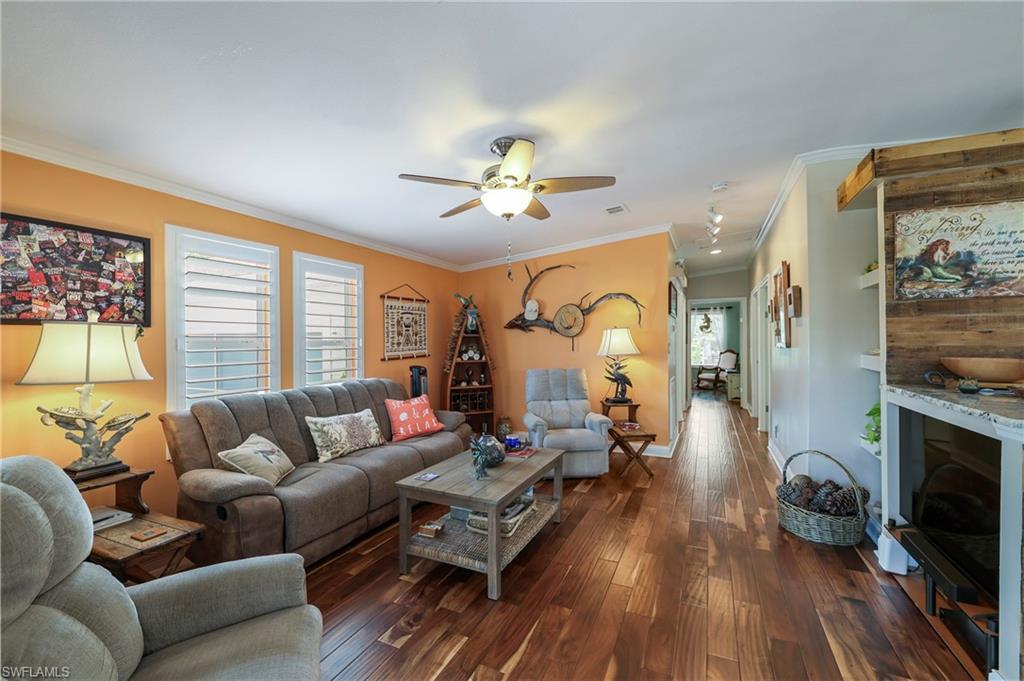 Spacious living area featuring wood-finish flooring, white crown molding, and a ceiling fan