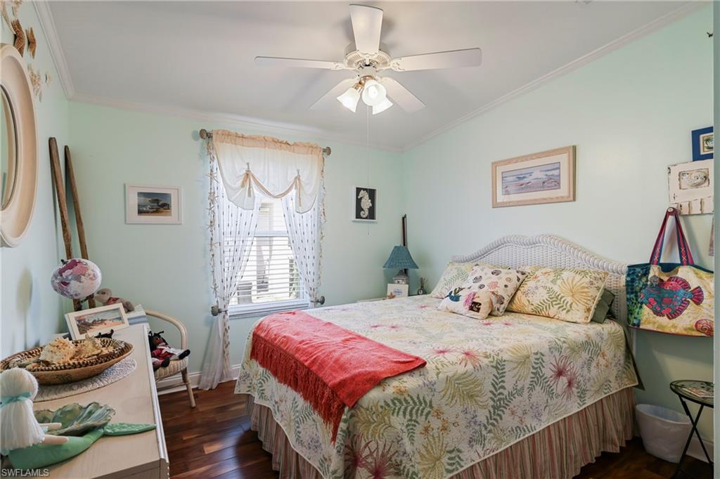 Inviting room featuring wood-finish flooring, a ceiling fan with light fixture, window with blinds and sheer curtains, and crown molding