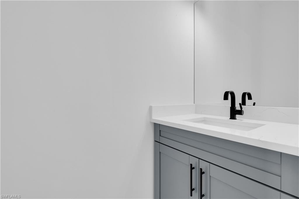 Light gray vanity with black hardware, white countertop, integrated sink, and matte black faucet