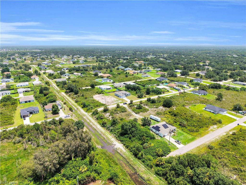 Expansive aerial showcasing a residential area with dispersed single-story homes, surrounded by abundant natural greenery