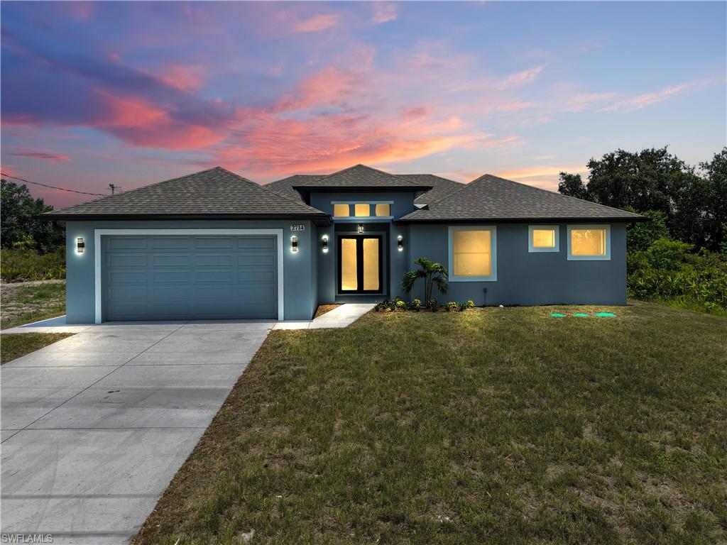 Contemporary single-story residence featuring a two-car garage, a covered entry, and a symmetrical facade with multiple windows