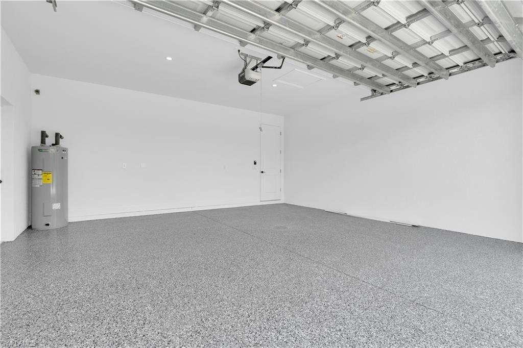 Spacious garage featuring a durable epoxy-coated floor, bright white walls, recessed lighting, and a modern garage door opener mechanism