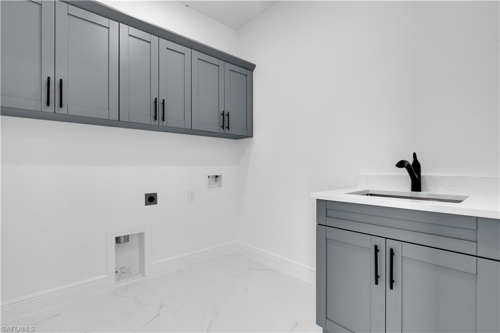 Utility space featuring light gray upper cabinetry with black hardware, a base cabinet with a built-in sink and matte black faucet, and white countertop