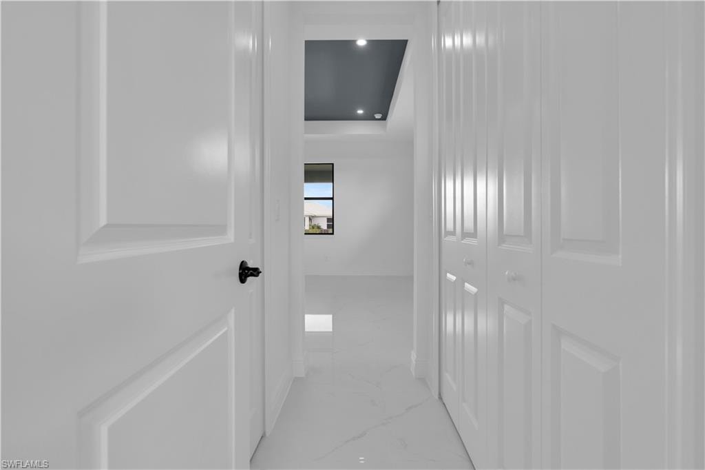 Hallway featuring white paneled doors, white bi-fold closet doors, and white tile flooring