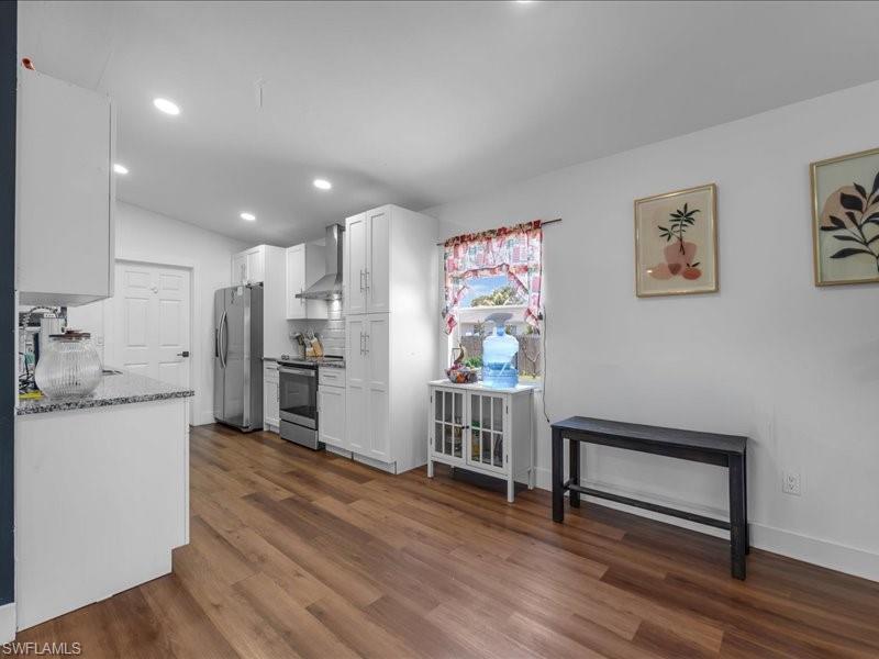 Kitchen featuring wood-finish flooring, white cabinetry, recessed lighting, stainless steel appliances, and granite-style countertops
