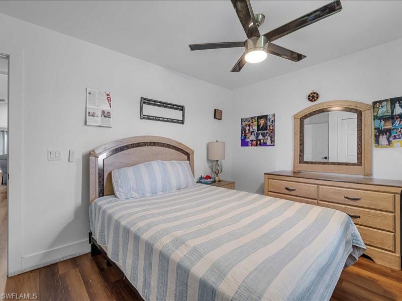 Bedroom featuring wood-finish flooring, a contemporary ceiling fan with integrated lighting, and white baseboards
