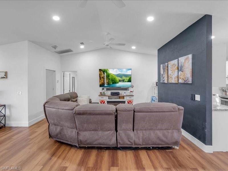 Spacious living area featuring wood-finish flooring, vaulted ceilings, and recessed lighting