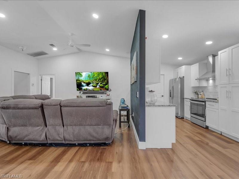 Open-concept living area with vaulted ceilings, recessed lighting, and wood-finish flooring throughout