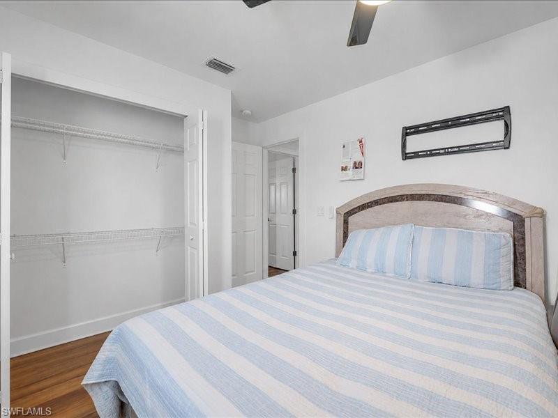 Bedroom featuring wood-finish flooring, a bi-fold closet with wire shelving, a ceiling fan, and a wall-mounted bracket