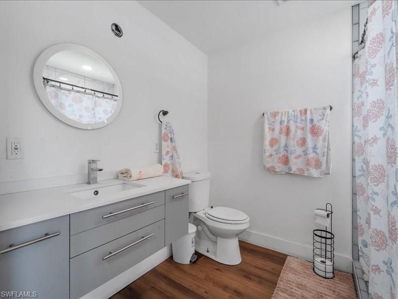 Bathroom featuring a floating vanity with a light gray finish, a white countertop with an integrated sink, and wood-finish flooring