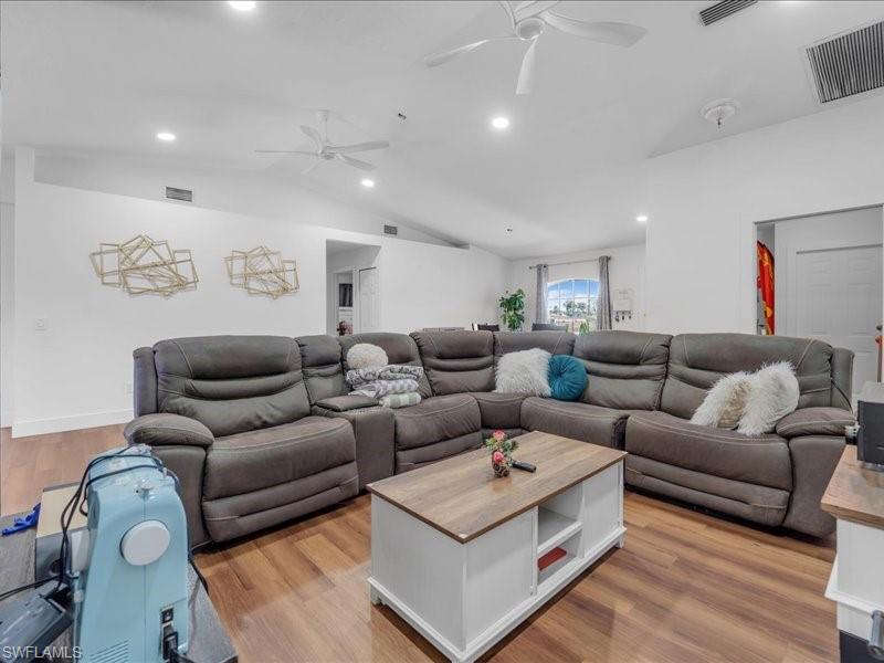 Spacious living area featuring wood-finish flooring, vaulted ceilings, recessed lighting, and dual ceiling fans