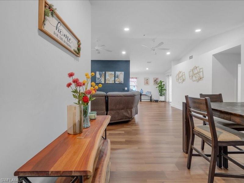 Open-concept living space featuring wood-finish flooring, recessed lighting, and a vaulted ceiling with ceiling fans