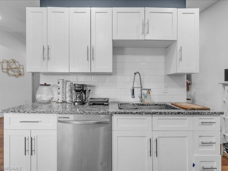 Kitchen featuring white shaker-style cabinetry with brushed nickel hardware, granite countertops, white subway tile backsplash, stainless steel dishwasher, and a gooseneck faucet