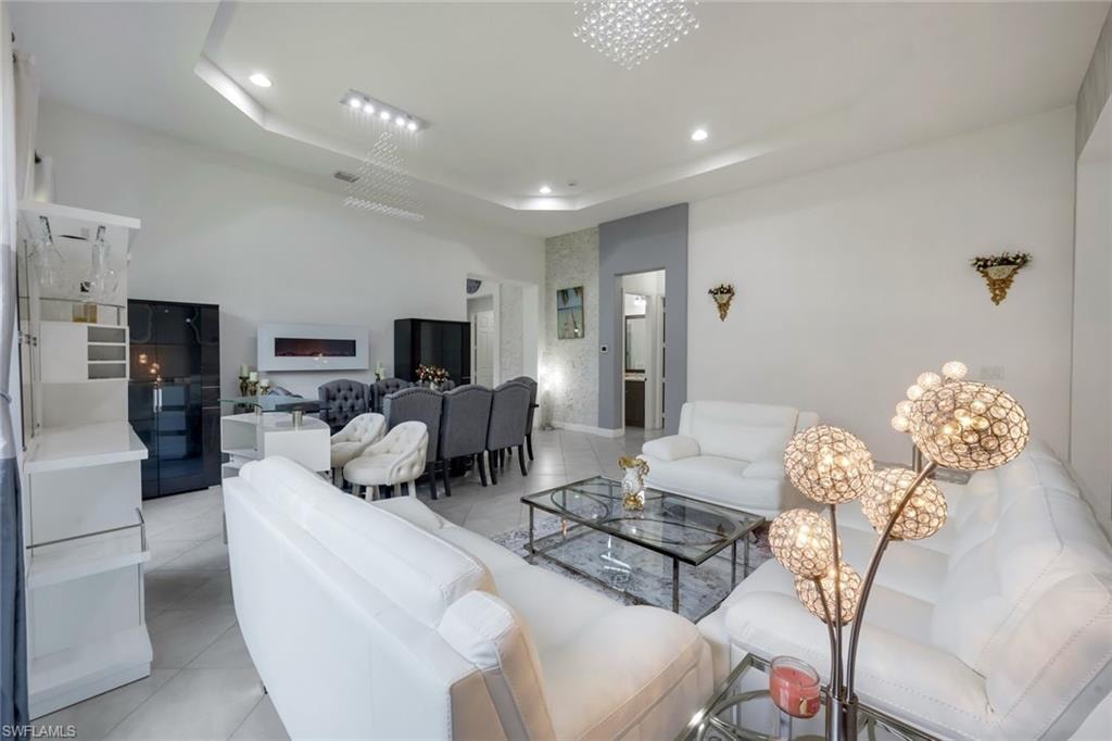 Spacious open-concept interior featuring light-toned tile flooring, recessed lighting, and a tray ceiling