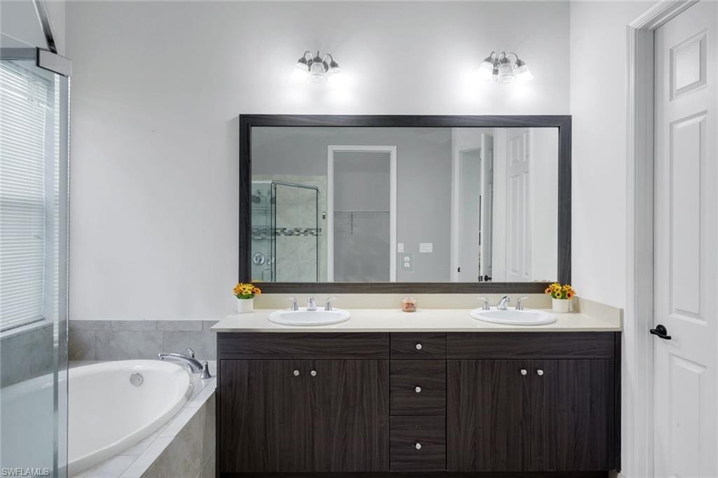 Dual-sink vanity with wood-finish cabinetry, light-toned countertop, and an expansive framed mirror