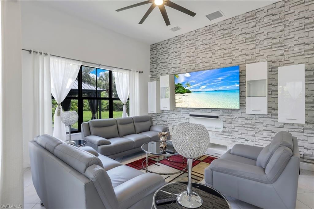 Living space featuring a textured stone-finish accent wall with integrated cabinetry, high ceilings, large format windows with exterior scenery, and a ceiling fan