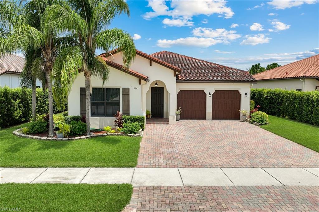 Mediterranean-style residence featuring a tile roof and a paver driveway