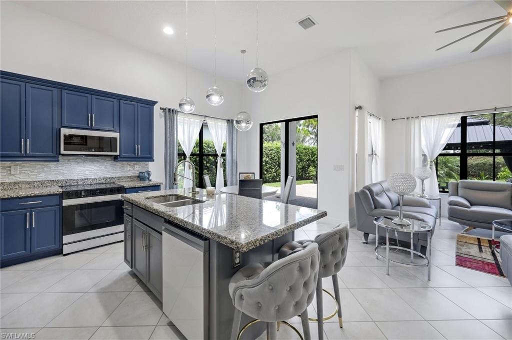 Open concept living space featuring a modern kitchen with blue cabinetry and stainless steel appliances