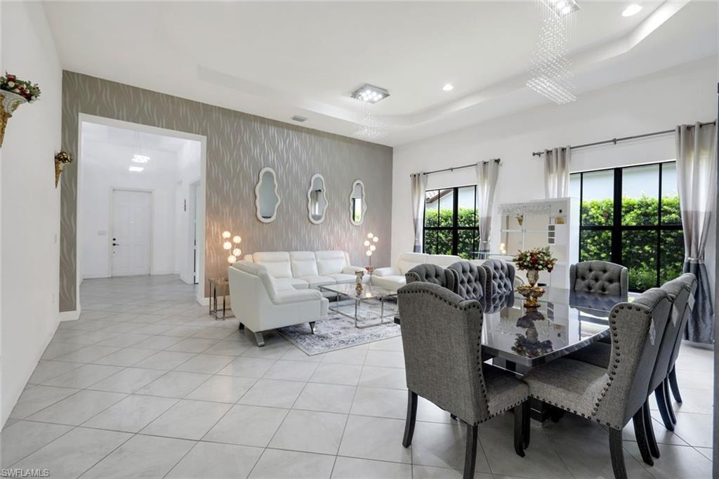 Spacious interior featuring tile flooring, a tray ceiling with recessed lighting, and large windows
