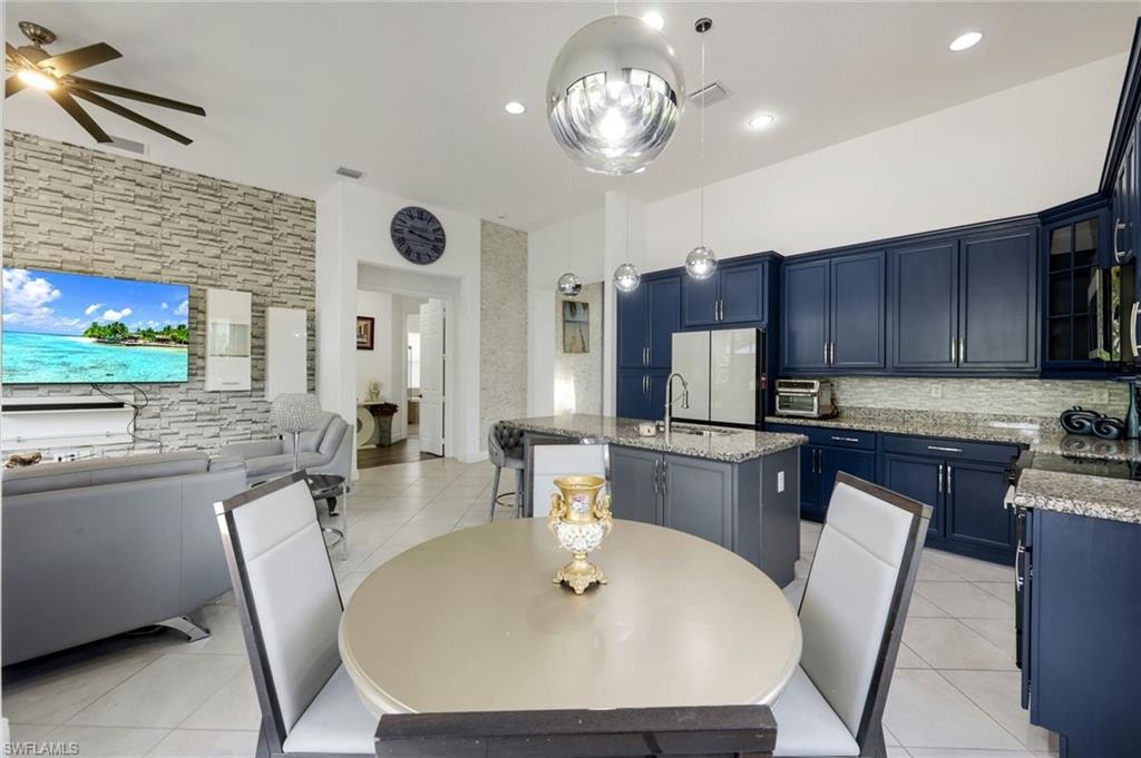 Spacious open-concept living area featuring a modern kitchen with blue cabinetry and granite countertops