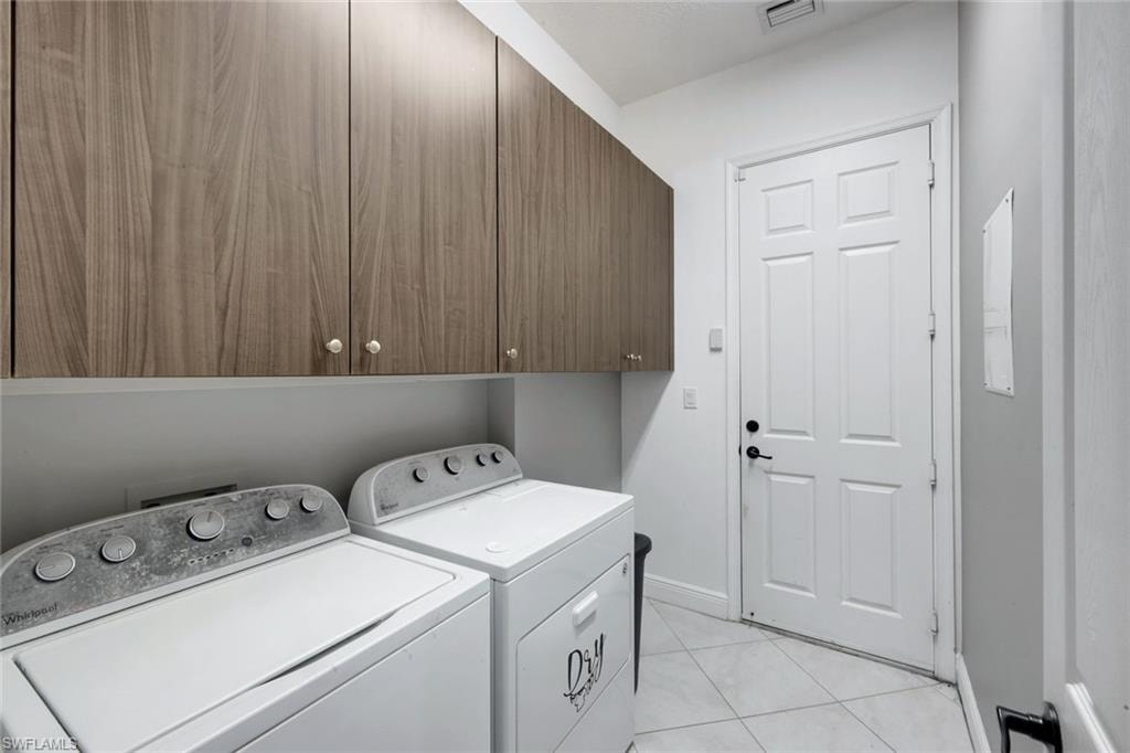 Dedicated utility area featuring wood-finish cabinetry, white paneled door, and tiled flooring