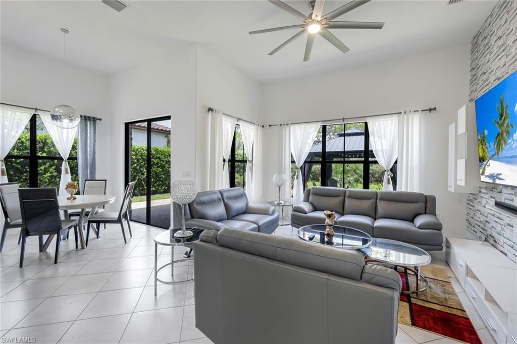 Open-concept living space featuring vaulted ceilings, abundant natural light from multiple windows, and a modern ceiling fan