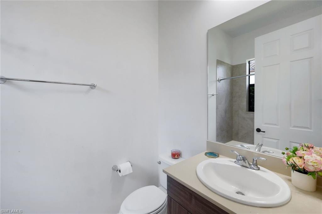 Bathroom featuring a vanity with a light-toned countertop and an integrated sink, a large wall-mounted mirror, and a white toilet