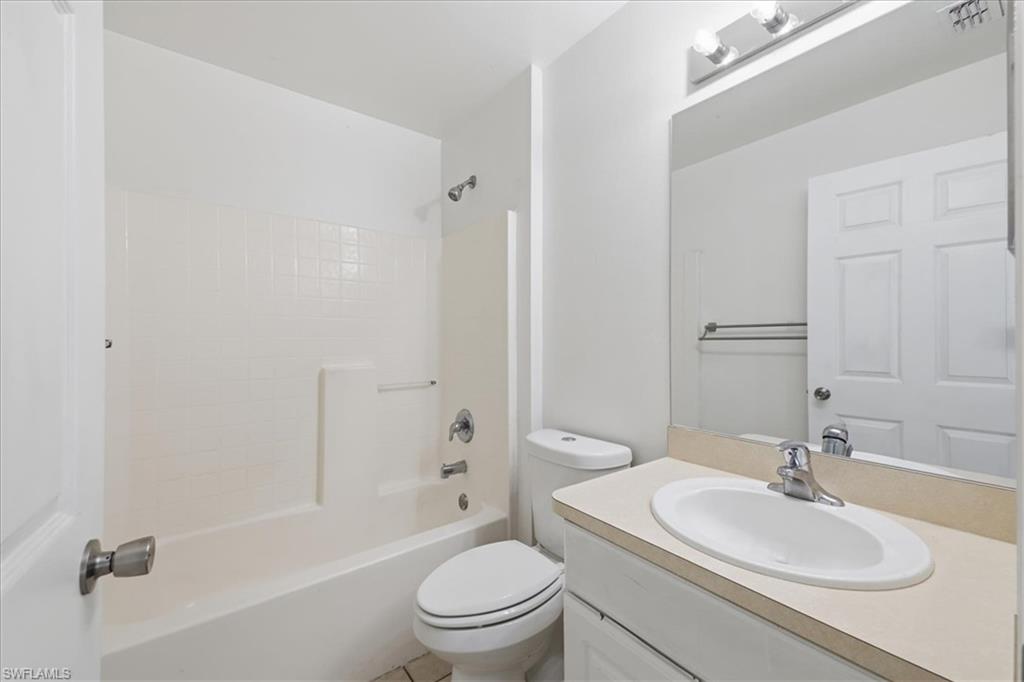 Bathroom featuring a white vanity with an oval basin sink, a large wall-mounted mirror, a tub/shower combination with white subway tile surround, and a chrome faucet