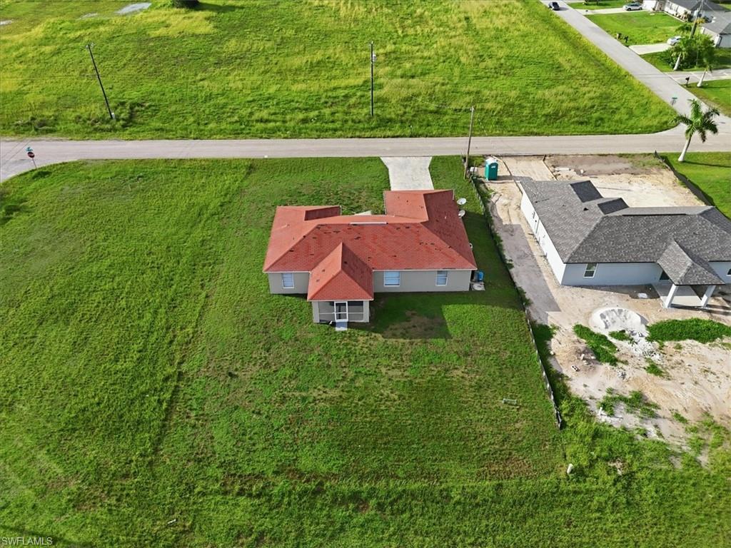 Expansive green lot featuring a single-story residence with a red tile roof