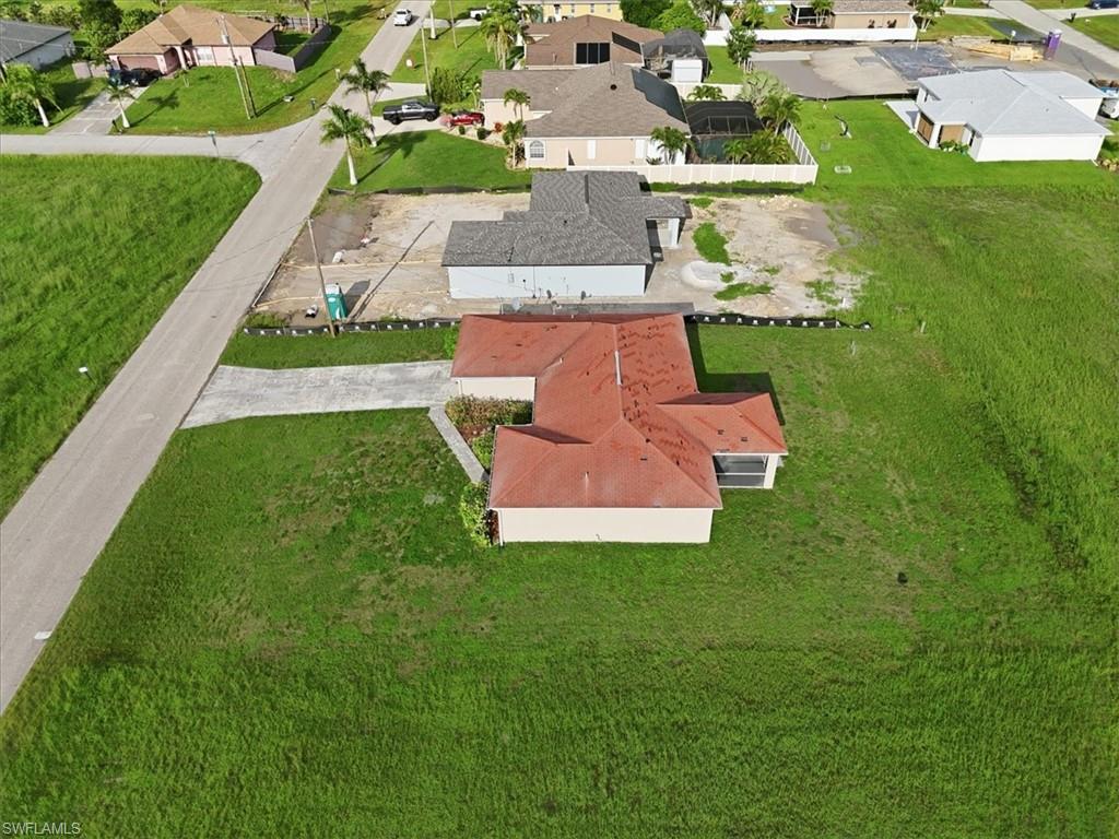 Single-story residence with a red tile roof and light-colored siding, featuring a paved driveway and surrounding green lawn