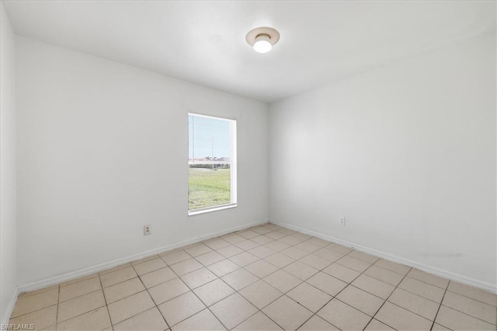 Room featuring neutral-toned tile flooring, white baseboards, and a single window with horizontal blinds