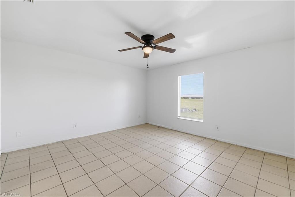 Spacious room featuring neutral-toned tile flooring, a contemporary ceiling fan with integrated lighting, and a single window