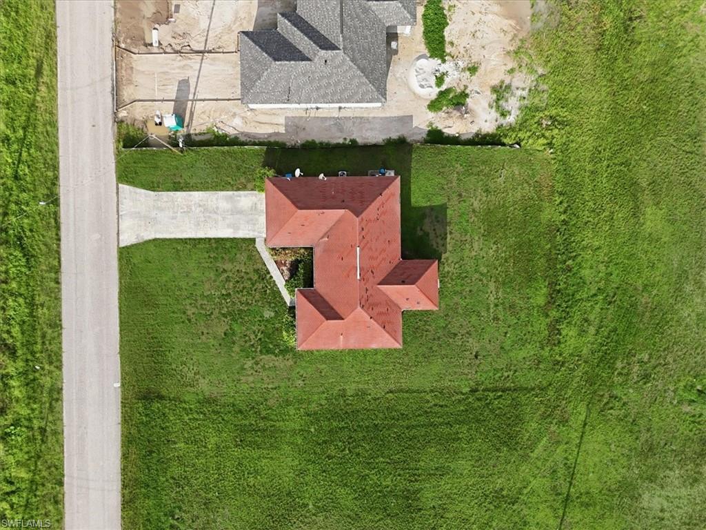 Spacious property featuring a red tile roof, concrete driveway, and ample green space
